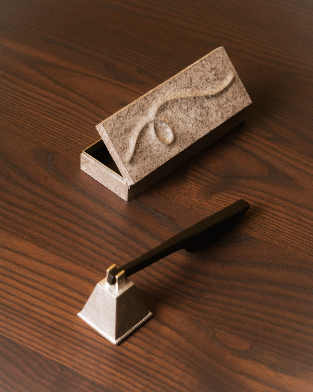 Decorative metal box and candle snuff on a wooden surface
